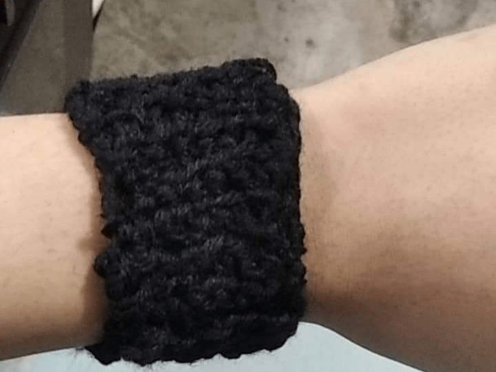 a black cuff made of yarn, black feels silky and cold.